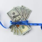 100 bills dollars wrapped tape measure cost of los ezdsen4 scaled.jpg